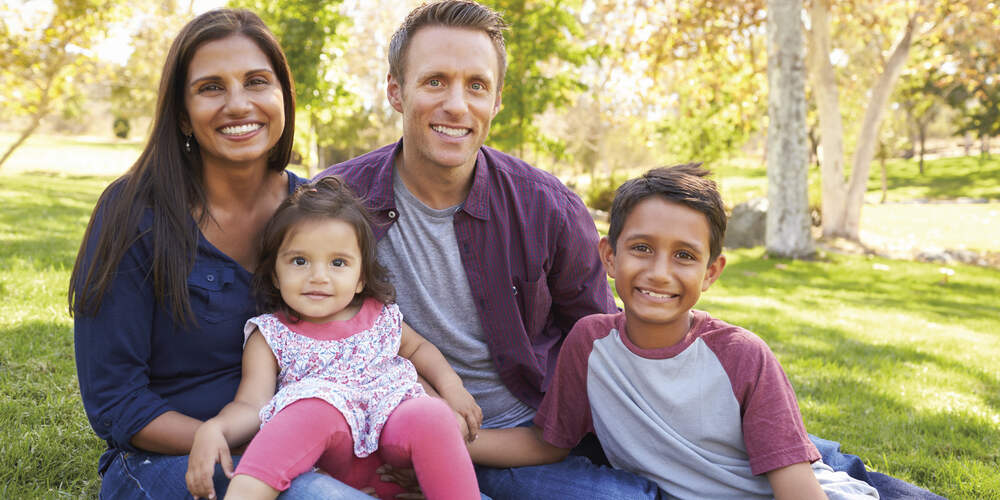 Family of 4 sitting on grass